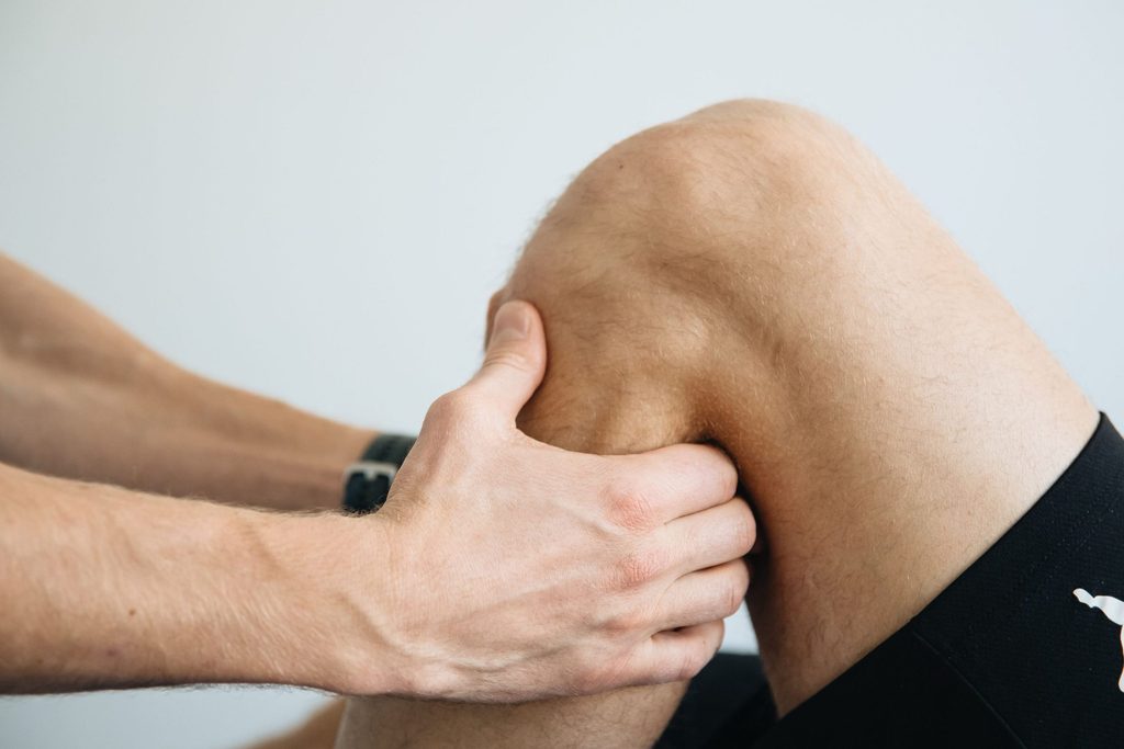 Mãos sobre o começo do joelhos flexionado, representando avaliação de fisioterapia